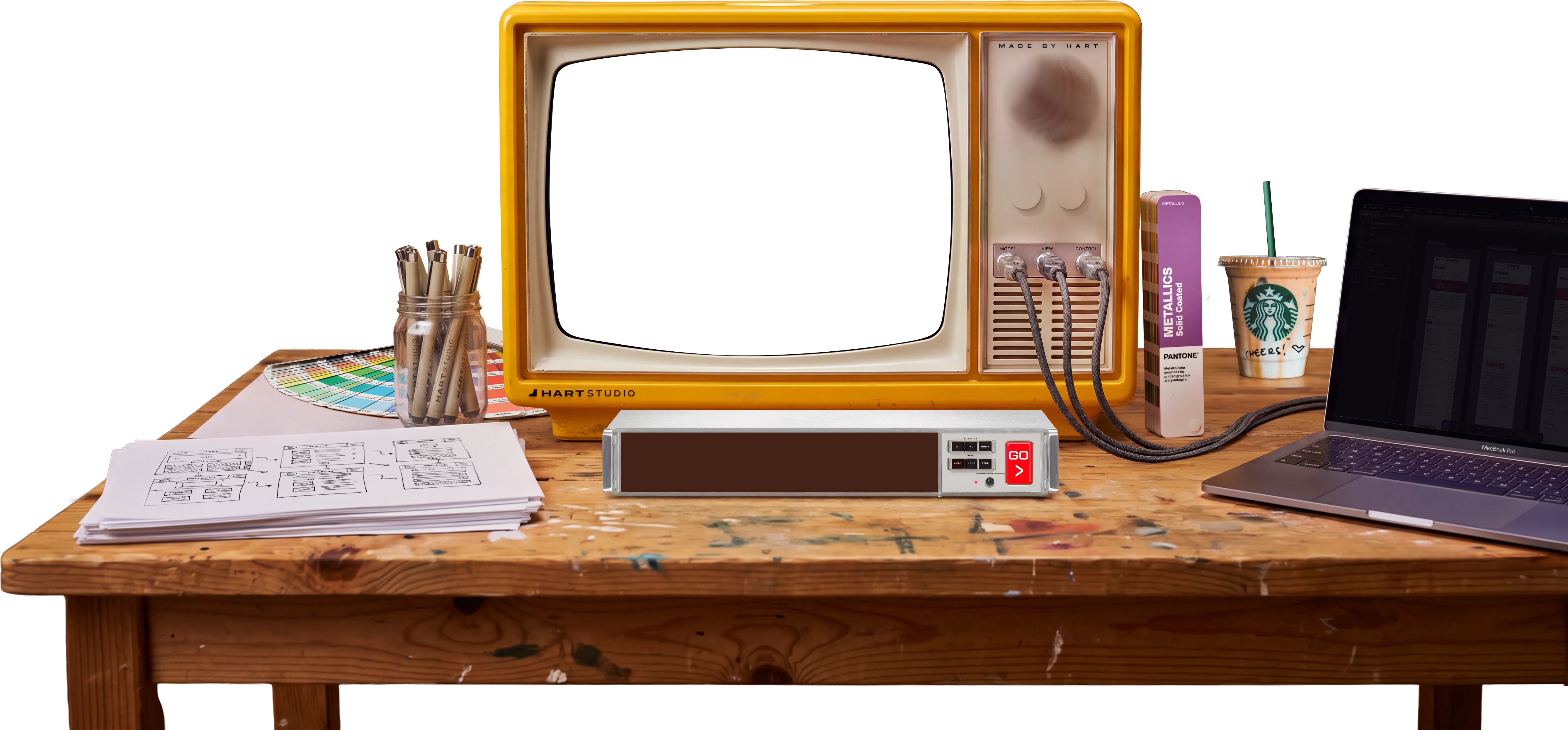 A vintage yellow television on a designer's desk, its screen showing Hart Studio project work